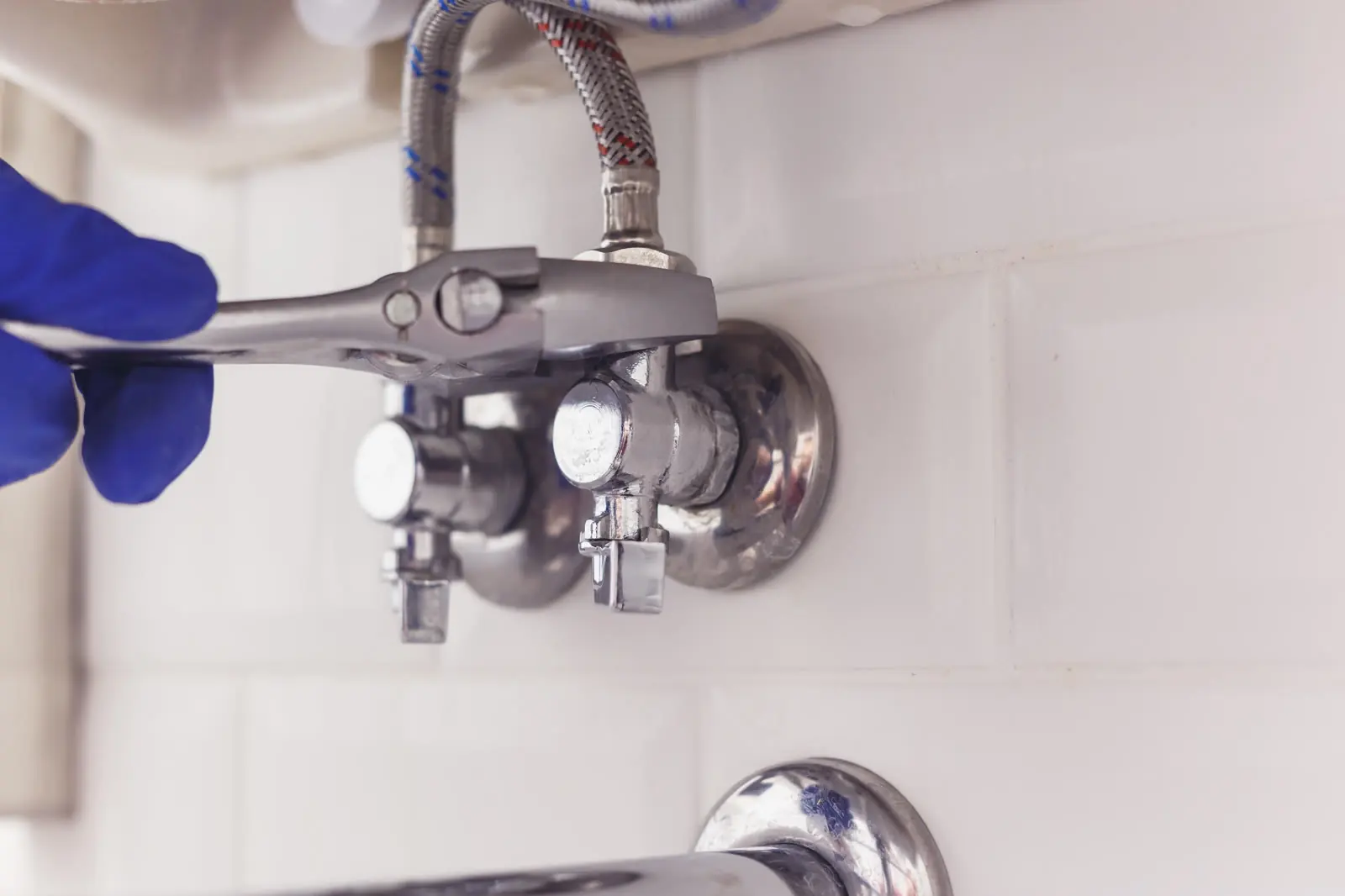 Plombier resserrant un robinet d'arrêt sous un lavabo